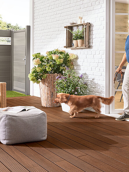 Dame und Her mit Hund im Garten vor einem BPC Zaun