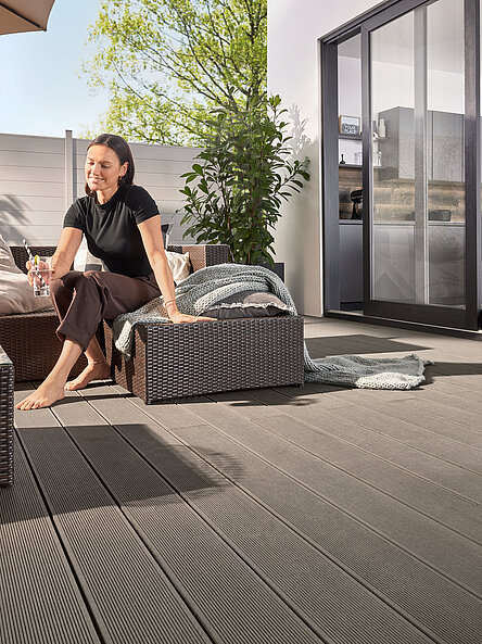 Frau auf moderner grauen Terrasse mit grauem Zaun